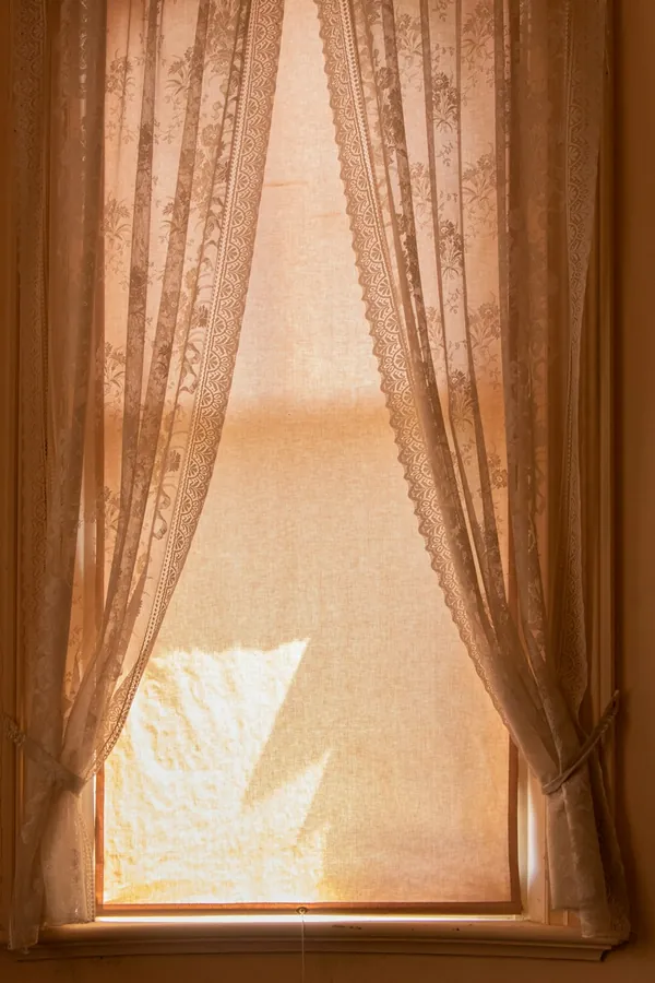 Lace curtains at a window with warm light