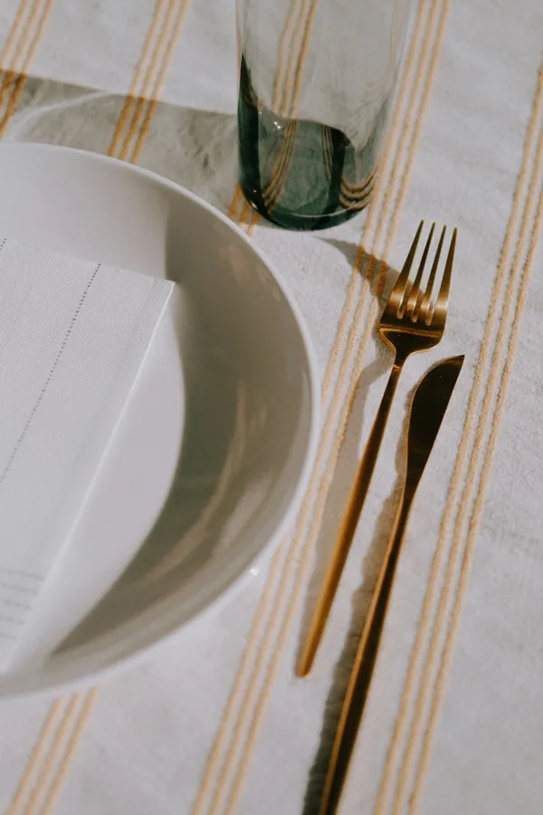 Place setting on a striped table cloth with a linen napkin