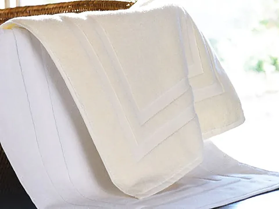Cream cotton bath mat towel draped over a rail