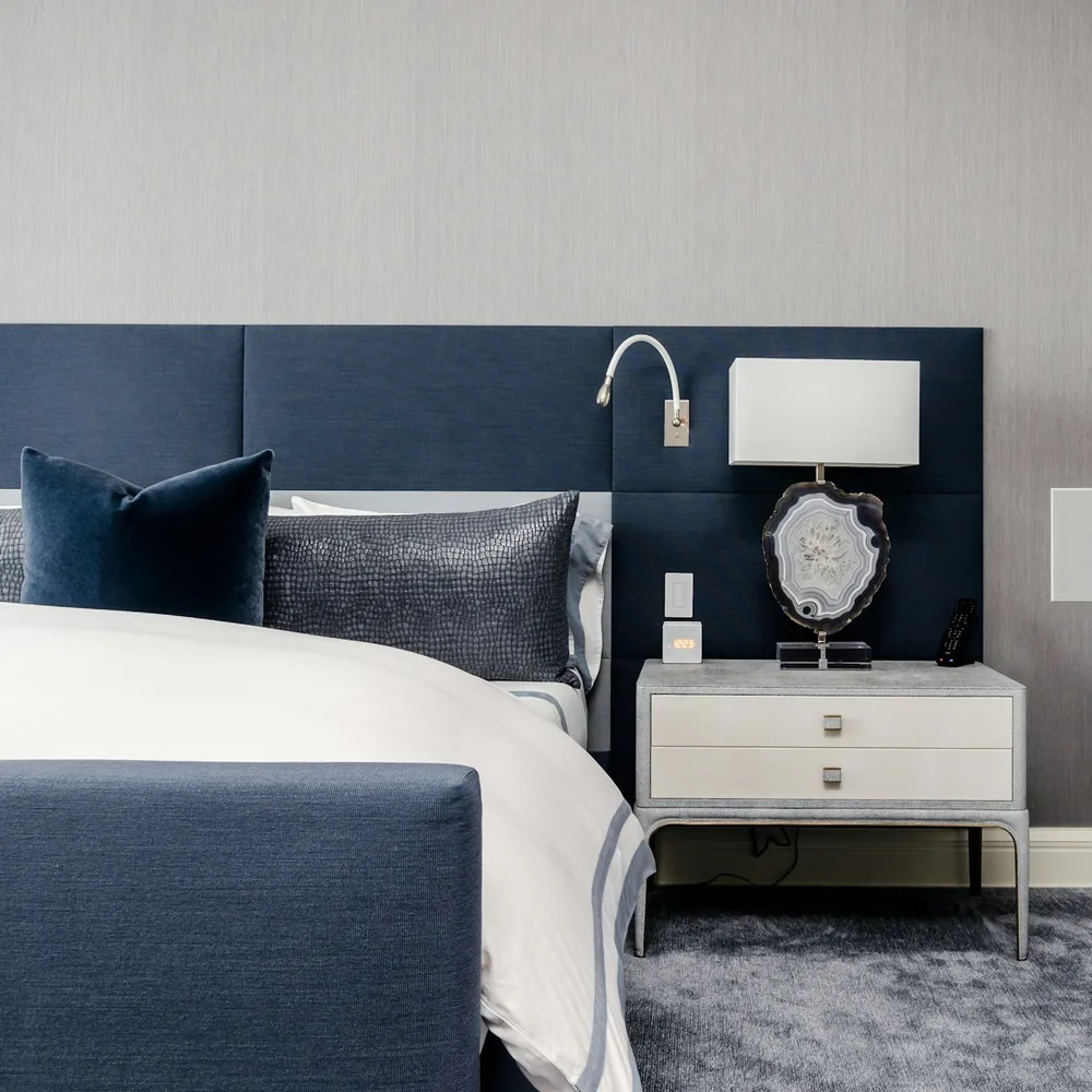 Hotel bed with white linen against a navy headboard