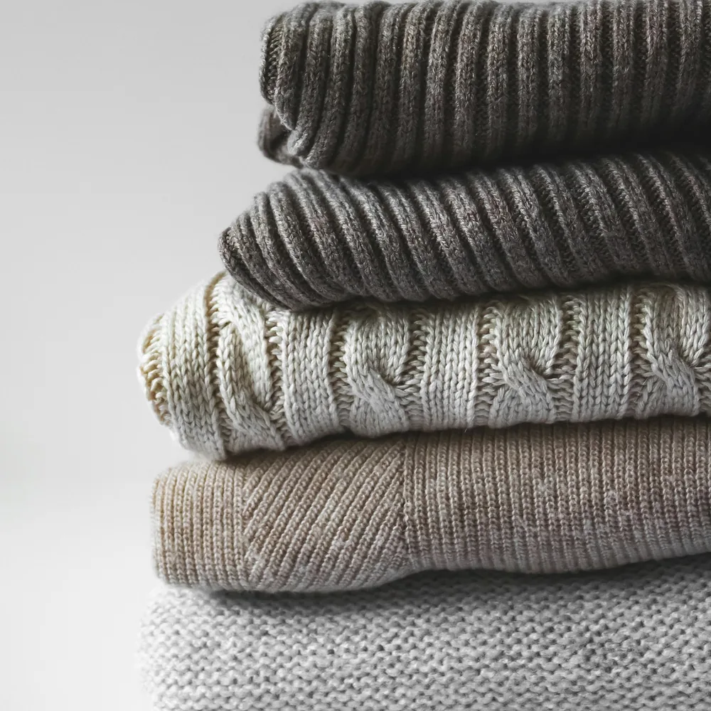 Stack of folded knitwear in grey and beige