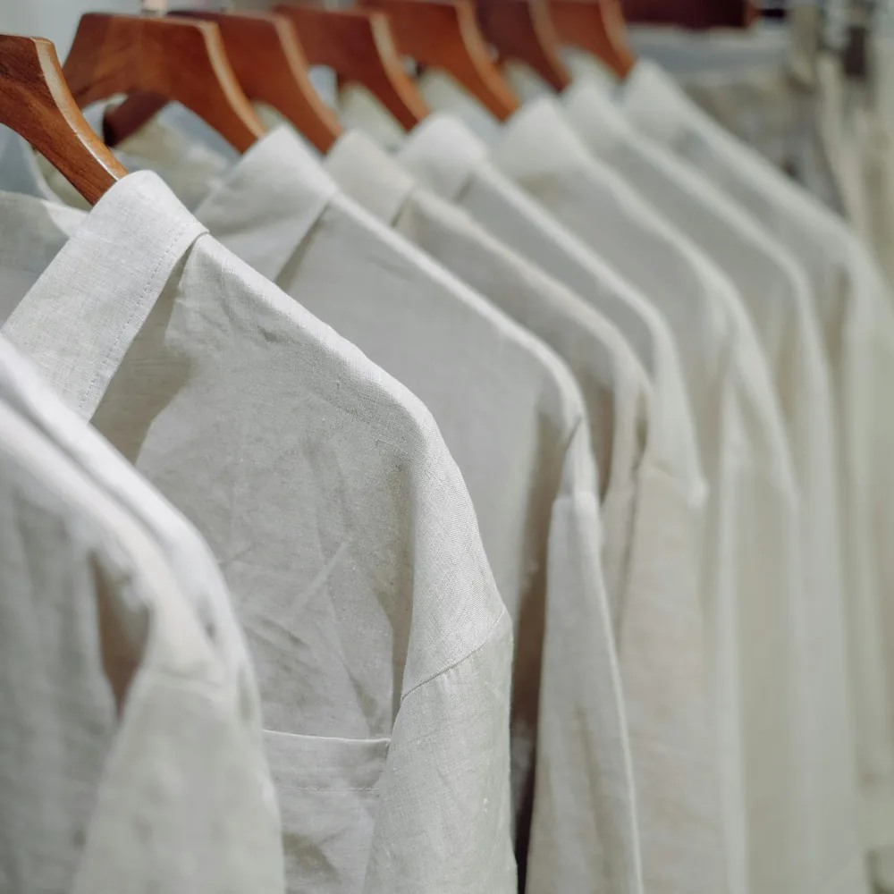 Row of plain off-white shirts on wooden hangers