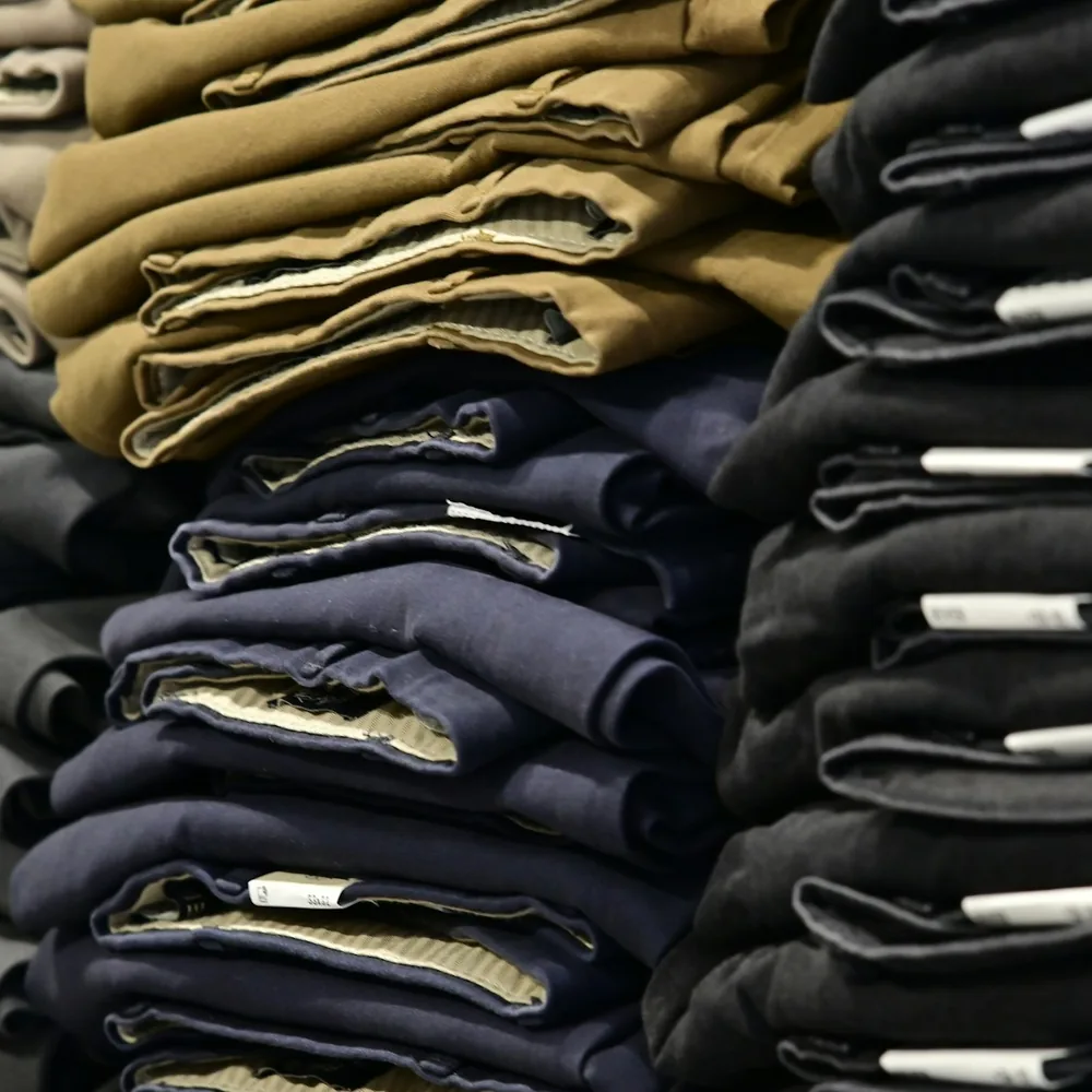 Folded trousers in khaki, navy and black stacked on shelves